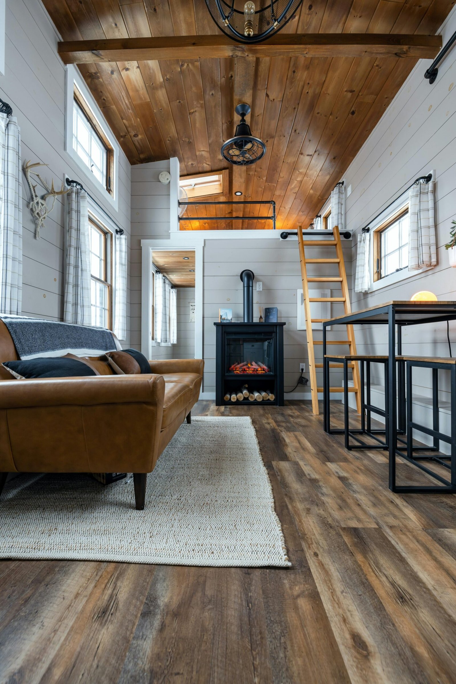Inviting tiny home interior with wooden ceiling and cozy furniture, vertical view.